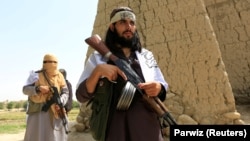 FILE: Taliban fighters walk as they celebrate ceasefire in Ghanikhel district of the eastern Nangarhar Province in June.