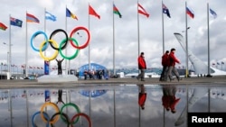 People walk past the Olympic rings beside Sochi's Olympic Park amid preparations continue for this year's Winter Games. 