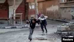 Children run across a street to avoid snipers in Deir al-Zor, Syria, earlier this year. A Britain-based nongovernmental organization says nearly 8,000 children have died in Syria's civil war. 