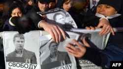 Opposition supporters hold posters bearing portraits of detained opposition activist Leonid Razvozzhayev during a rally in central Moscow on October 30.