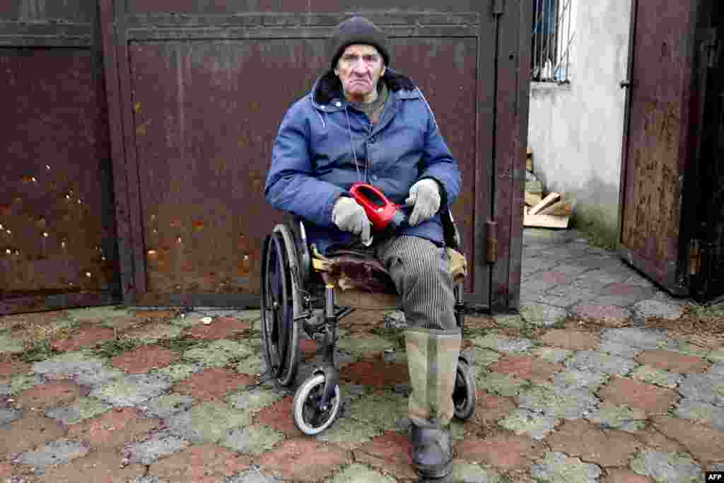 Viktor Gudelya, who lost a leg in shelling in 2014, watches firemen battle a blaze after his house in Avdiyivka was destroyed as a result of heavy shelling by Russia- backed rebels on February 26. (AFP/Anatolii Stepanov)