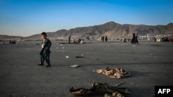 Момче минава покрай захвърлени военни униформи на летището в Кабул, 16 август 2021.