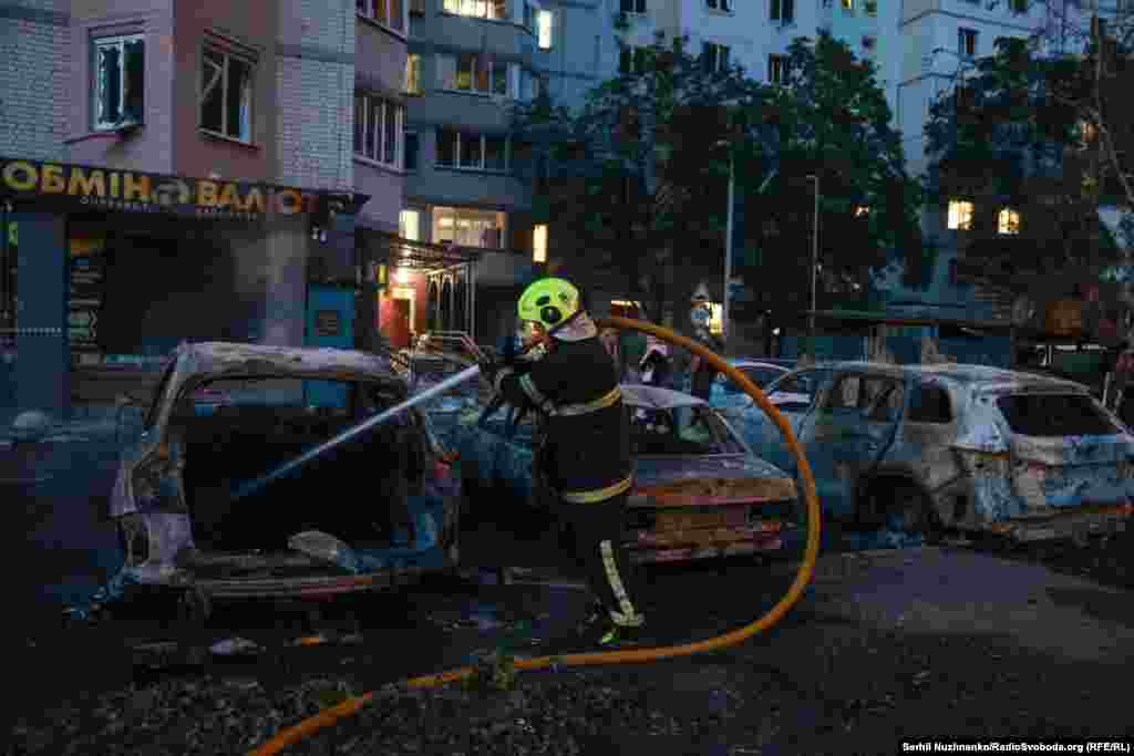 Рятувальник гасить машини, що загорілися внаслідок атаки