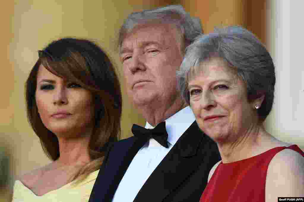 U.K. -- (L-R) US First Lady Melania Trump, US President Donald Trump and Britain's Prime Minister Theresa May stand on steps in the Great Court as the bands of the Scots, Irish and Welsh Guards perform a ceremonial welcome as they arrive for a black-tie d