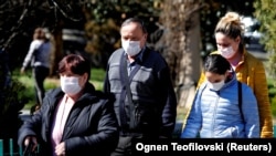 People walk with covered faces to protect against the coronavirus at the state hospital in Skopje, North Macedonia.