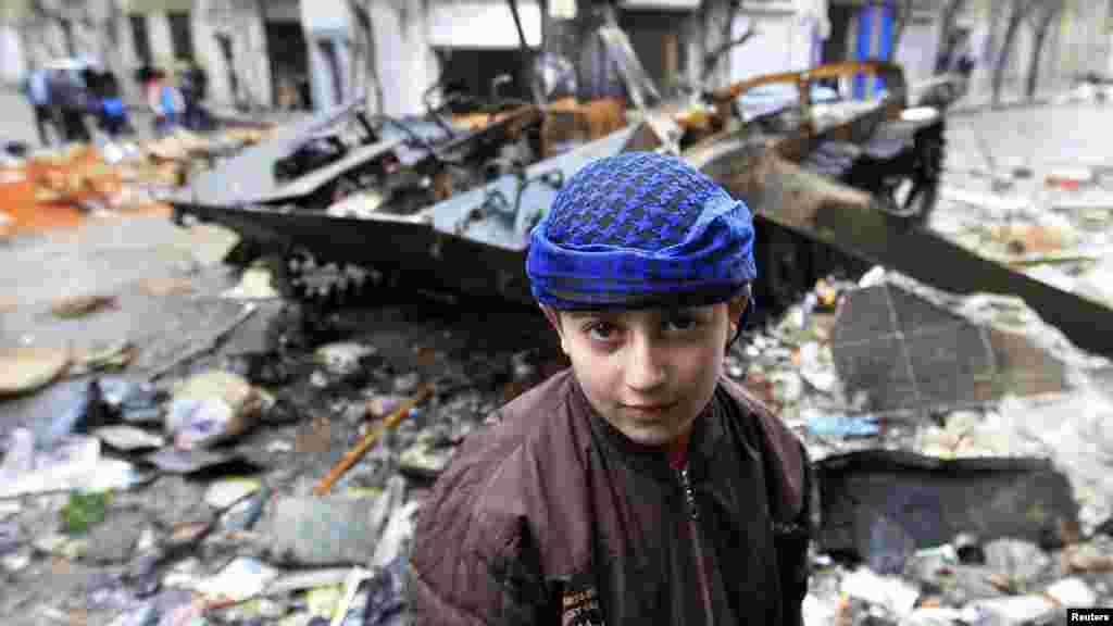 სირიელი ბიჭი 23 იანვარს ქალაქ ჰომსში, სირიის არმიის დამსხვრეულ ჯავშანტრანსპორტიორთან. (AFP/Ali Al-Saadi)