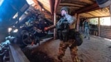 In this Russian Defense Ministry image, a Russian soldier prepares to fire a howitzer at a Ukrainian position. 
