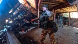 In this Russian Defense Ministry image, a Russian soldier prepares to fire a howitzer at a Ukrainian position. 