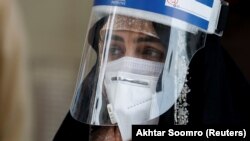 A woman wears a protective face shield and a protective face mask as she attends an event of mask distribution along a road, as the outbreak of the coronavirus disease (COVID-19) continues in Karachi, Pakistan on June 15.