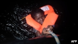 A migrant holds onto a rope during a rescue operation off Libya's Mediterranean coastline earlier this year. Others have not been so lucky.