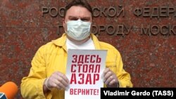 Журналистът Александър Плюшчев държи малък плакат, на който пише "Тук стоя Азар", по време на протест в подкрепа на арестувания журналист Иля Азар на 28 май в Москва