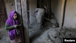 A man (R) clears rubble after part of his house collapsed after an earthquake, in Rodat district of Jalalabad province in October.