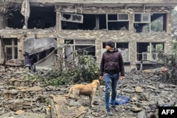 A man and his dog walk across the rubble of a building at the site of an Israeli airstrike in south Beirut on March 15.