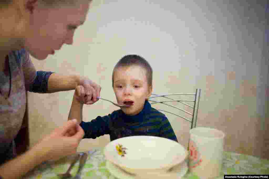 Yuliya teaching a young boy to hold a spoon. As well as providing care and raising money for children suffering from cerebral palsy, Yuliya trained as a speech therapist to better care for her daughter and other children affected by the disease.&nbsp;