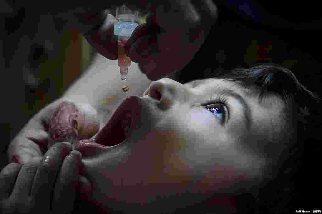 A health worker administers polio vaccine drops to a child in Karachi, Pakistan.