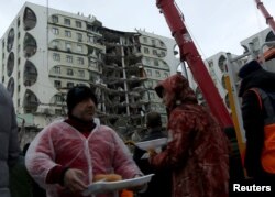 Banorët me nga një shujtë që u shpërnda pranë një ndërtese të dëmtuar pas tërmetit në Diyarbakir, Turqi