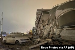 Пошкоджені автомобілі припарковані перед будівлею, зруйнованою внаслідок землетрусу, в Діярбакирі, на південному сході Туреччини, 6 лютого 2023 року
