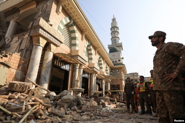 A Pakistani soldier and rescue workers survey the damage after a suicide blast in a mosque in Peshawar in January 2023.