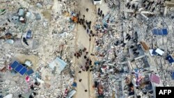 Një pamje nga lart tregon banorët që vazhdojnë kërkimet për të mbijetuar mes rrënojave të ndërtesave të shembura pas tërmetit në fshatin Besnia në provincën veriperëndimore të Idlibit të Sirisë, të kontrolluar nga opozita, në kufi me Turqinë. 7 shkurt 2023.