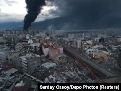 Черный дым от пожаров поднимается над уничтоженным землетрясением центром турецкого города Искендерун. 7 февраля 2023 года