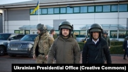 Președintele ucrainean Volodimir Zelenski și premierul britanic Rishi Sunak cu căști de piloți de avioane de luptă, în vizită la baza militară Bovington, unde sunt antrenați militarii ucraineni, Marea Britanie, 8 februarie 2023. 