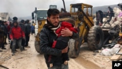 Мъж носи дете, намерено в развалини в град Бесни в сирийската провинция Идлиб, 6 февруари 2023 г.