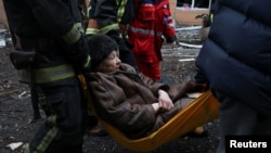 Rescuers carry a woman who was wounded inside a residential building by a Russian missile strike in central Kharkiv on February 5.