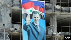 Suriyada döyüşlərdə xaraba qalmış yayaış binalarından birində prezident Bashar al-Assad-ın seçki portreti. 3 iyun 2014. 
