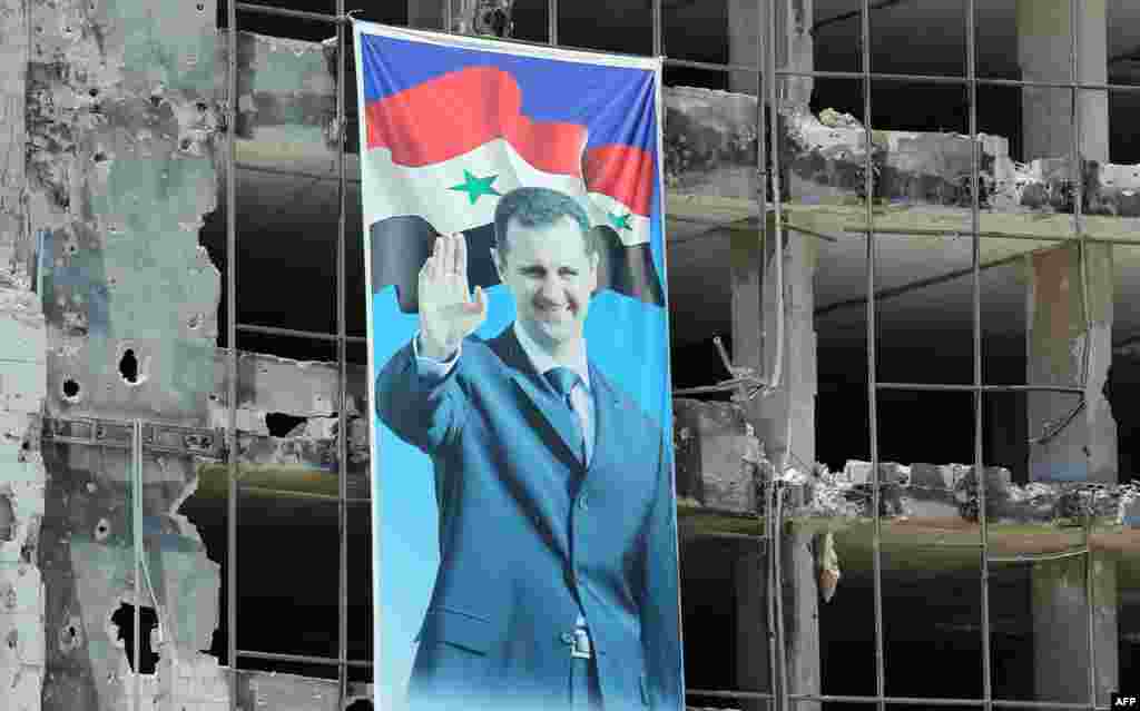 A banner with a picture of Syrian President Bashar al-Assad hangs on a destroyed building in the Homs neighborhood of Khaldiyeh. (AFP/Joseph Eid)