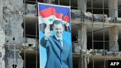 A banner with a picture of President Bashar Assad hangs on a destroyed building in the Homs neighborhood of Khaldiyeh.