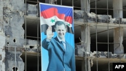 Syria -- A banner with a picture of President Bashar Assad hangs on a destroyed building in the Homs neighborhood of Khaldiyeh, June 3, 2014