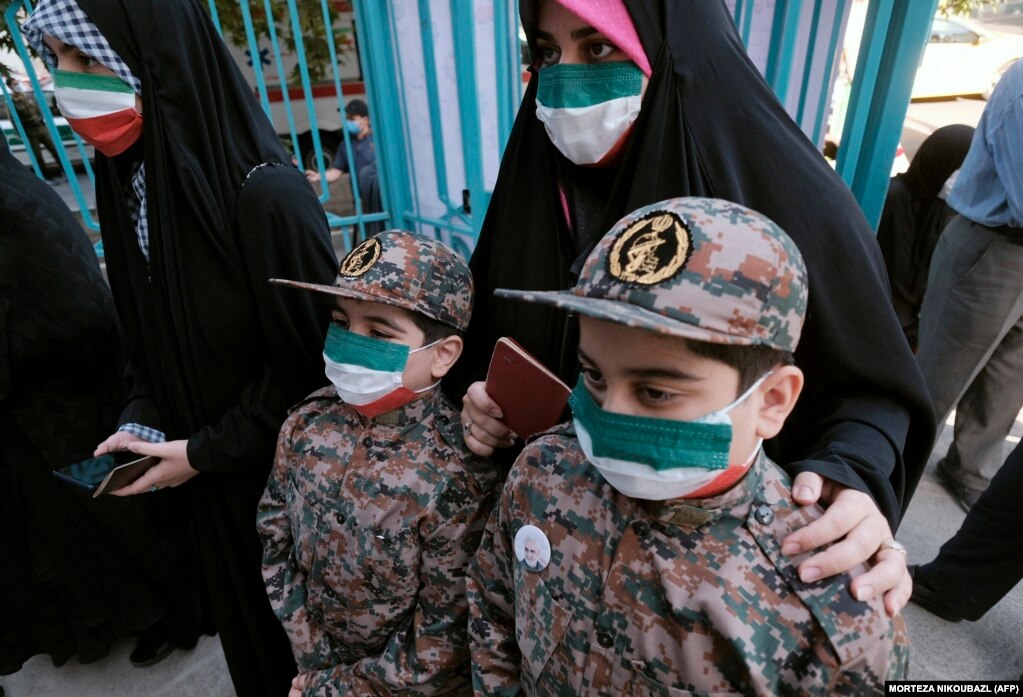Иранка и нејзините деца, облечени во униформи на Корпусот на Исламската револуционерна гарда, се редат на избирачко место за да го дадат својот глас на претседателските избори, 18 јуни 2021 година.