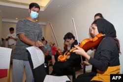 The conductor of the Afghan National Orchestra, Mohammad Qambar Nawshad, trains musicians of the Afghanistan National Institute of Music ahead of a concert in Doha, Qatar, on October 18.