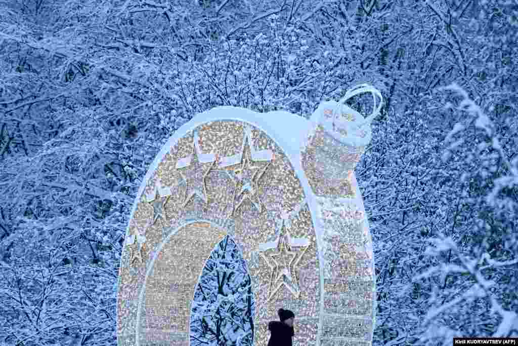 After heavy snowfall on the outskirts of Moscow, a woman walks past an arch of light that has been installed for the upcoming New Year and Christmas celebrations.&nbsp;