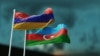 Armenian and Azerbaijani flags flutter in the wind against the evening sky.