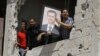 Сырыйцы у пашкоджаным будынку трымаюць партрэт прэзыдэнта Башара Асада падчас інспэкцыі назіральнікаў ААН, 14 чэрвеня 2012