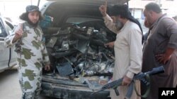 Syria -- Fighters from the Islamic State group gesture as they load a van with parts that they said was a US drone that crashed into a communications tower in Raqqa, September 23, 2014