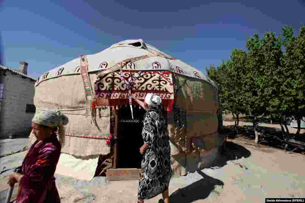 Astara Yusupova (right) and a relative help to decorate a yurt outside their home. Every year, family members work together to set up the yurt where they live during the summer.