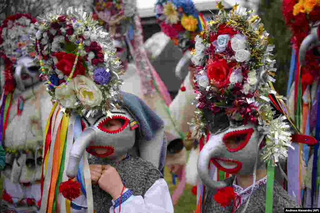 Copii mascați, îmbrăcați în costume populare, dansează într-un spectacol de tradiții de iarnă la Muzeul Satului din București. În tradițiile rurale pre-creștine, dansatorii îmbrăcați în costume colorate sau blănuri de animale, mergeau din casă în casă cântând și dansând pentru a alunga răul.