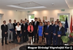 Középen Völner Pál, mellette rózsaszín felsőben Vízkelety Mariann korábbi államtitkár, mellette Schadl György, illetve tizenhárom újonnan kinevezett önálló bírósági végrehajtó 2019. augusztus 7-én