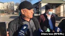 Еркара Жумабаев, отец Нурболата Жумабаева, разговаривает с журналистами у здания департамента полиции Шымкента. 9 декабря 2021 года