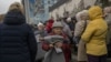 Local residents hold blankets and lamps during an aid distribution in the center of the newly liberated southern city of Kherson on November 17.