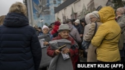 Local residents hold blankets and lamps during an aid distribution in the center of the newly liberated southern city of Kherson on November 17.