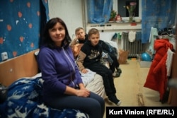 Olha Hrishanovich sits on her bed with her twin boys in their small dormitory room. They have no idea where they will live after March.