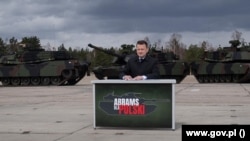 Міністр оборони Польщі Маріуш Блащак на тлі нових американських танків Abrams, придбаних його країною, 2022 рік