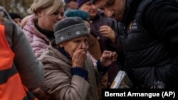 An elderly woman reacts after receiving food donations in Kherson on November 17.