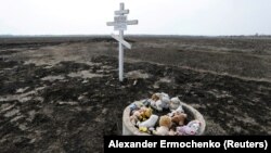 Toys are placed near a cross in memory of victims of the Malaysia Airlines Flight 17 plane crash in the village of Rozsypne in Ukraine's eastern Donetsk region in March 2020.