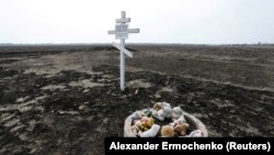 Jucăriile sunt plasate lângă crucea ridicată în memoria victimelor accidentului avionului MH17 în satul Rozsypne din regiunea Donețk