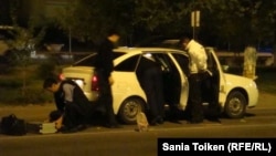 Полицейские досматривают машину на месте ночного вооруженного инцидента в центре города Атырау. 15 сентября 2012 года.