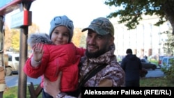 Serhiy, a Ukrainian soldier, holds a girl in liberated Kherson.